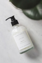Hand soap bottle labeled 'Drift' on a marble surface with a plant in the background