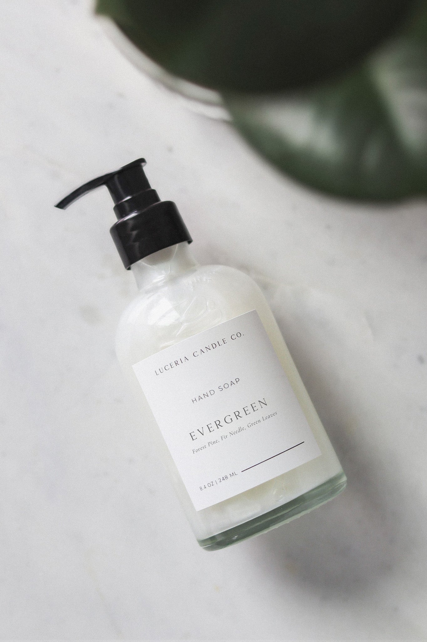 Hand soap bottle labeled 'Evergreen' on a marble surface