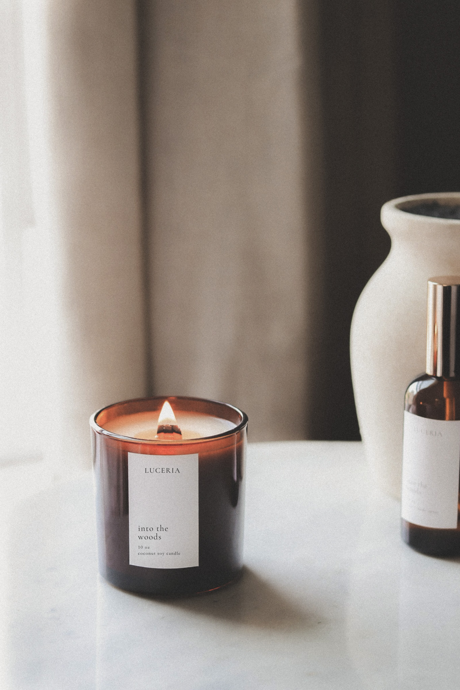 Luceria candle and bottle on a surface with a neutral background