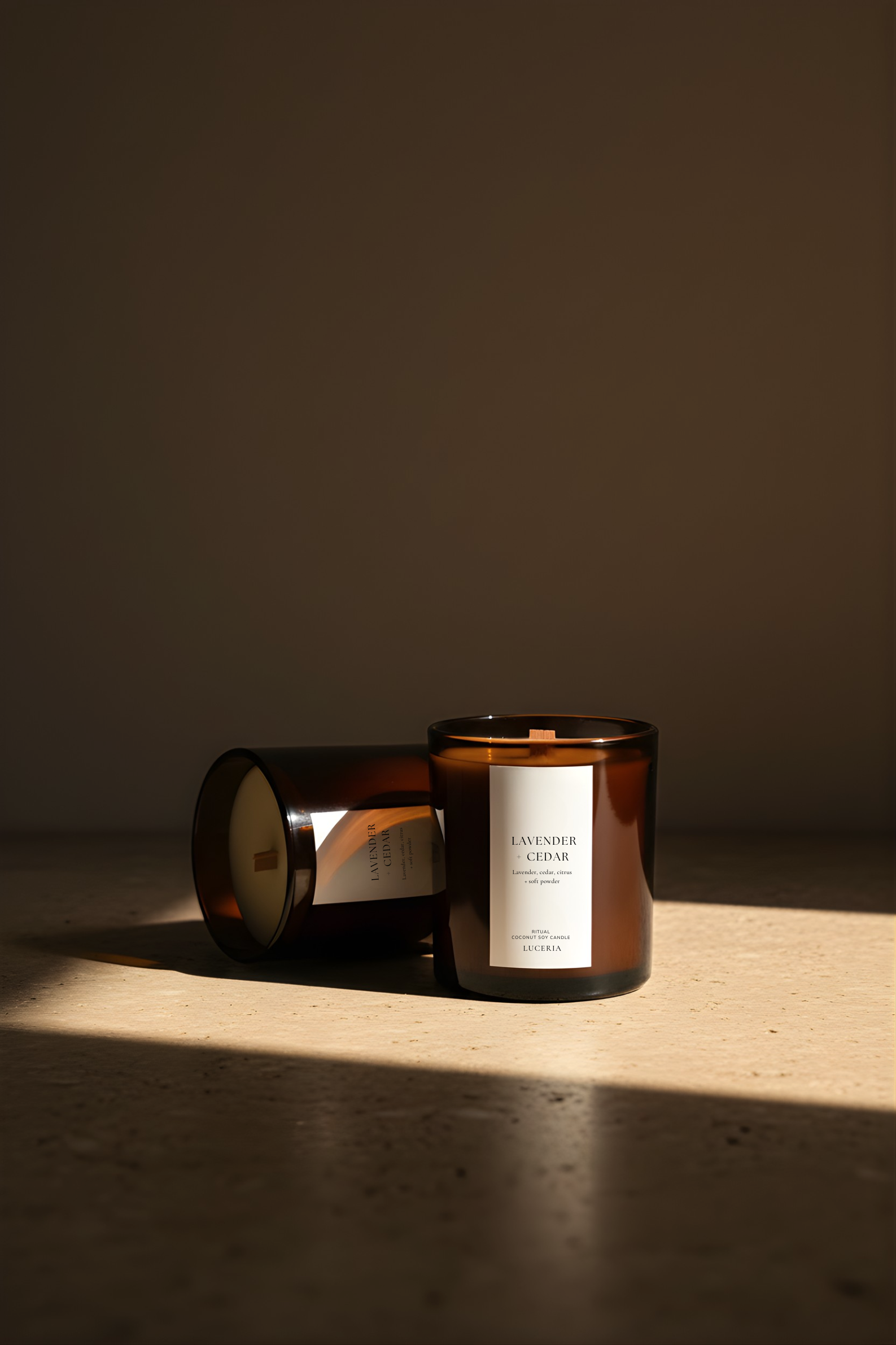 Two brown glass candles with labels on a wooden surface.
