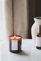 Amber candle and bottle on a surface with a neutral background