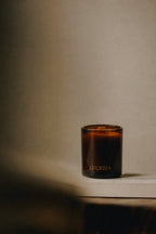 Dark amber glass candle with 'LUCERIA' branding on a neutral background