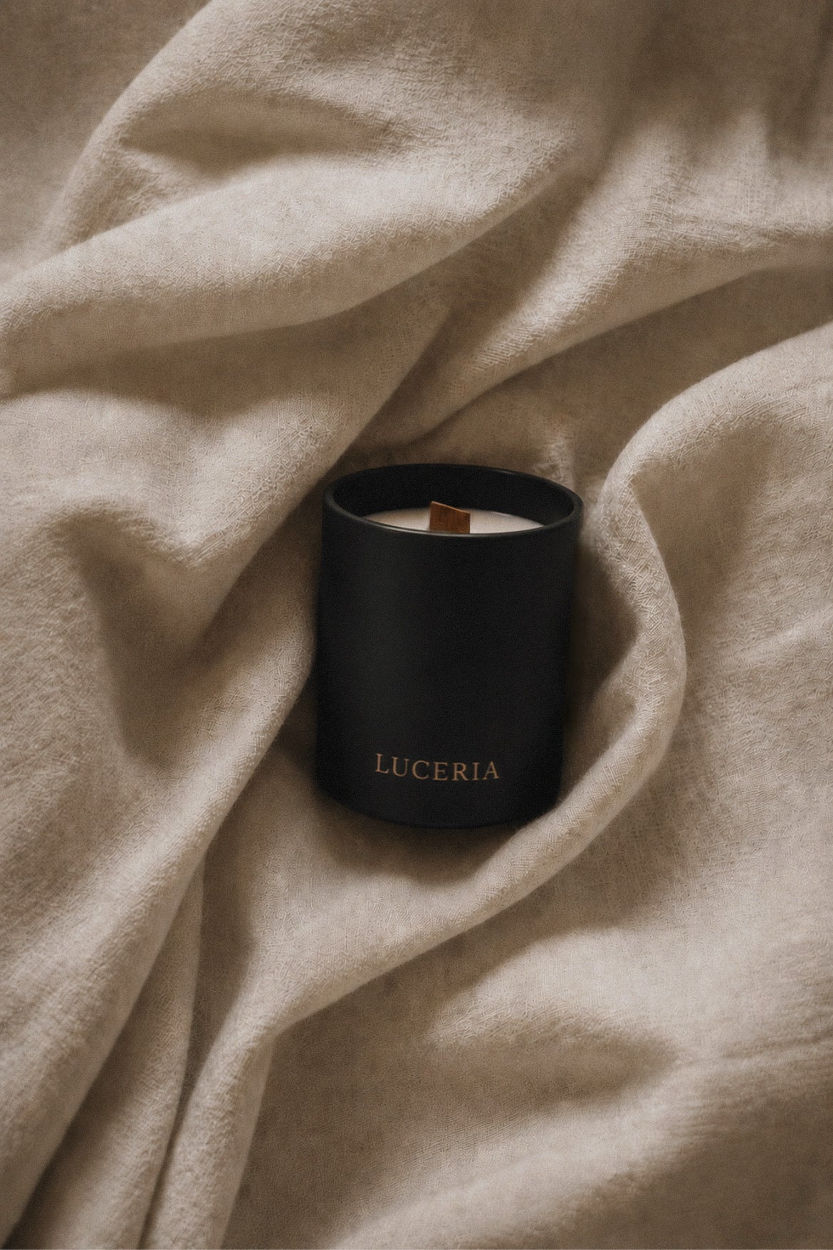 Black matte soy candle with LUCERIA branding on linen background