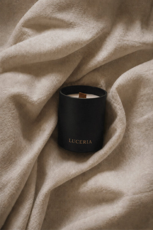 Black matte soy candle with LUCERIA branding on linen background