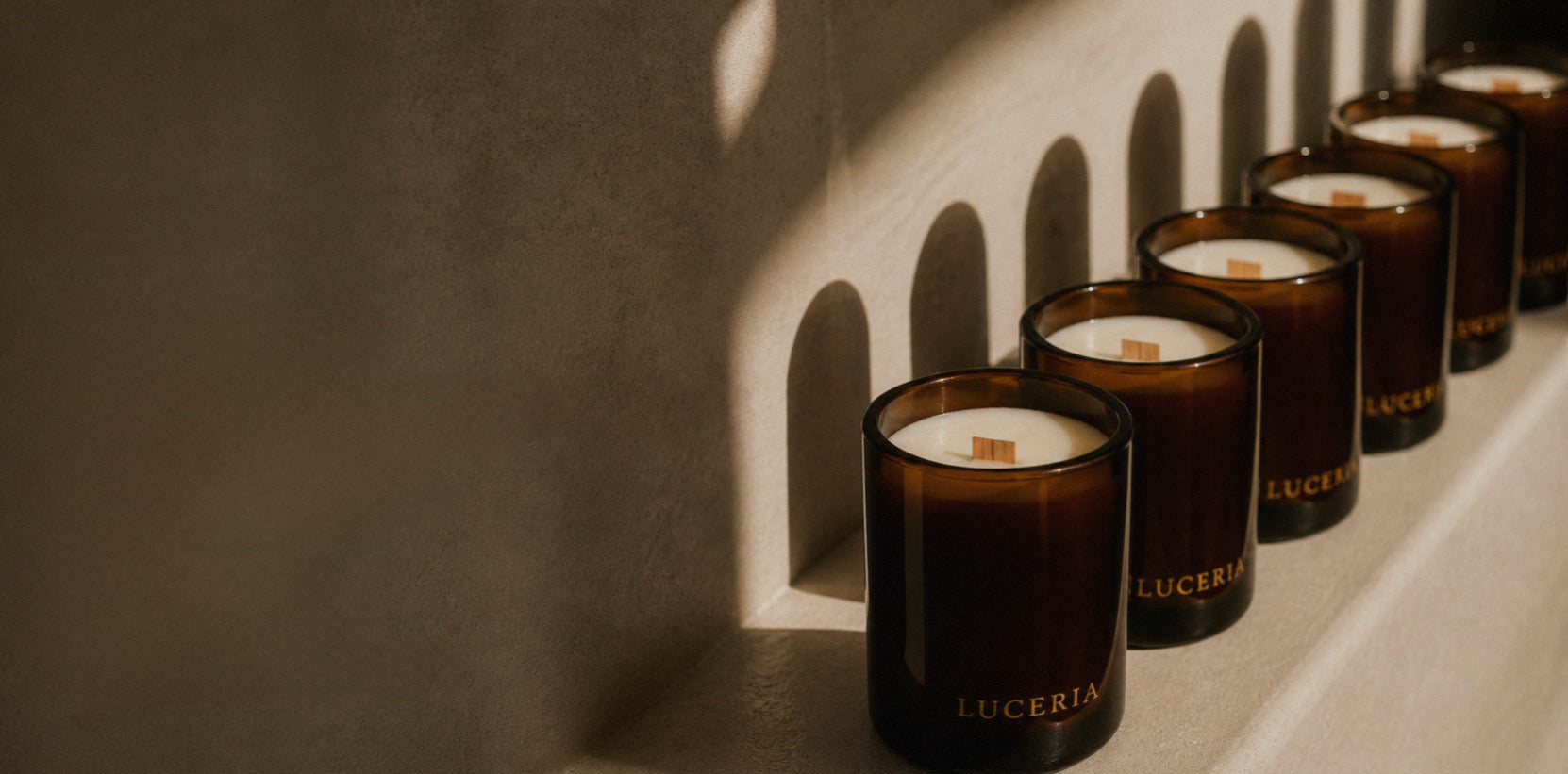 Row of amber candles with visible Luceria branding on a textured wall background
