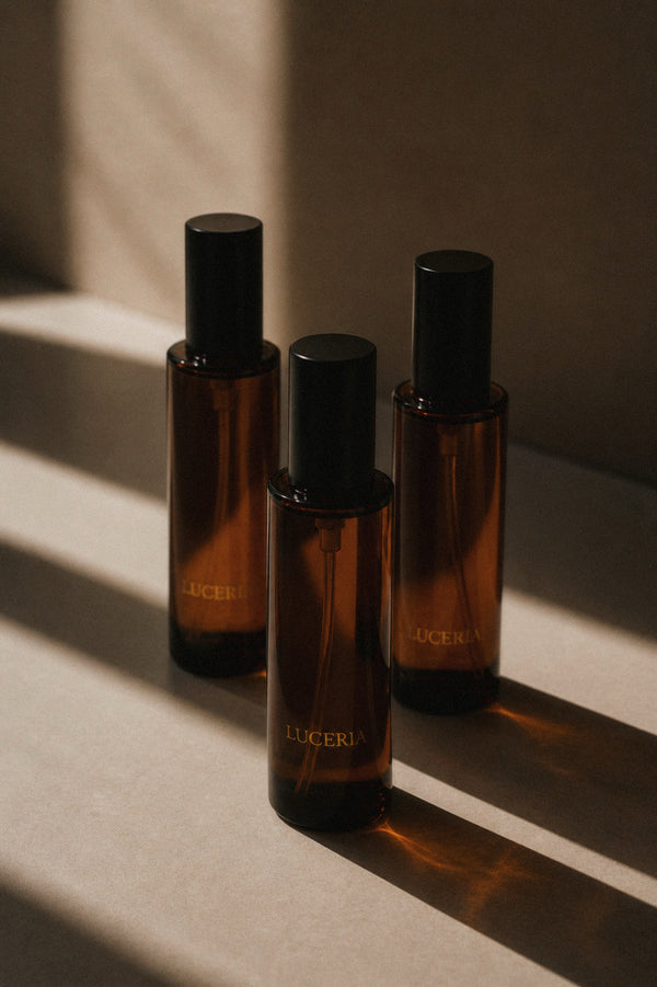 three black cap amber spray bottles with Luceria branding in a neutral ritualistic minimalist style