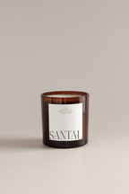 Coconut santal scented candle with a label on a beige background