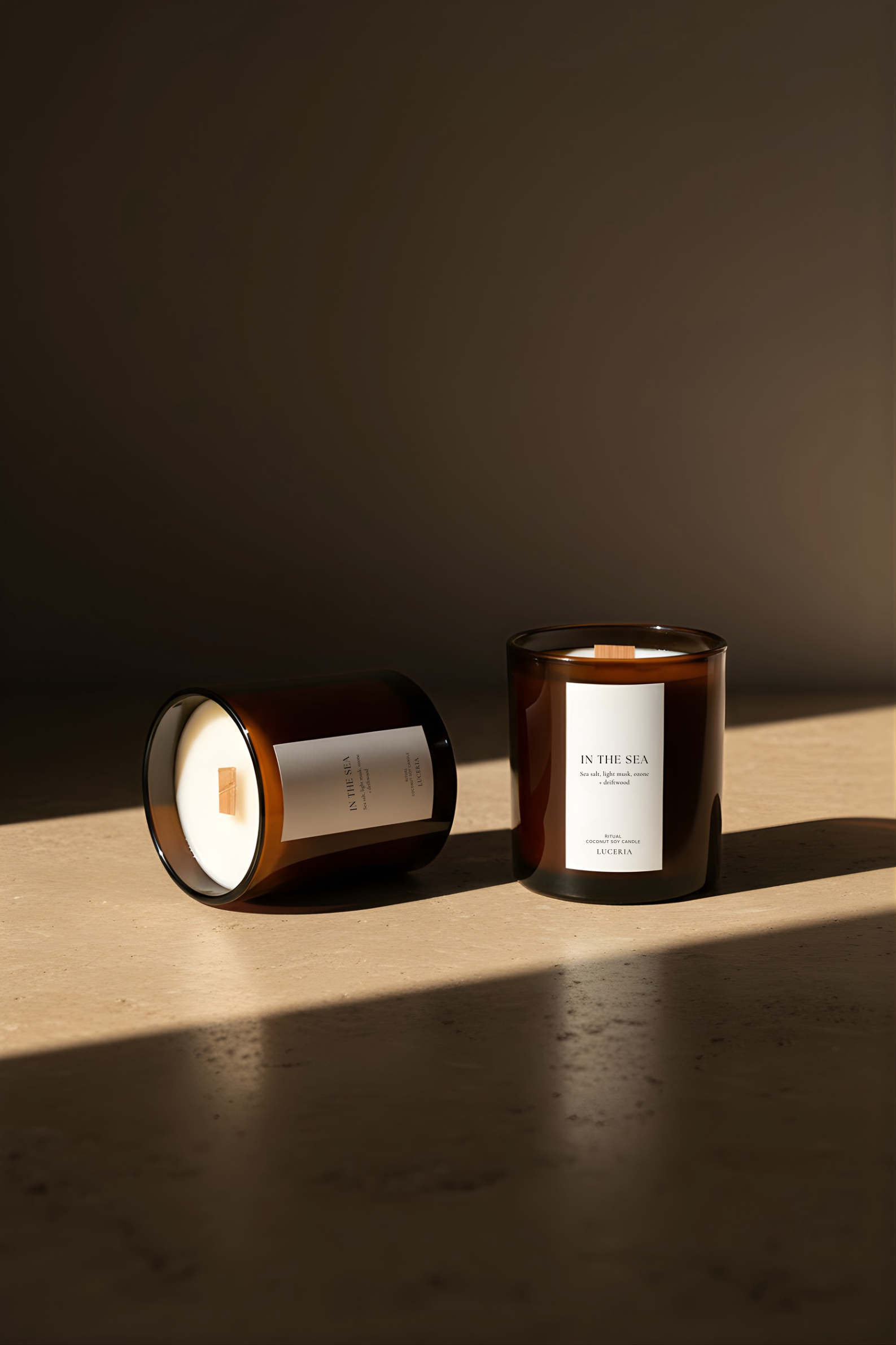 Two In the Sea candles with labels on a wooden surface and dark background