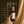 A hand holds a bottle of Luceria Sea Salt and Must room and linen spray against a warm background of dark brown curtains and beige drapes. White text overlays describe the product's features and specifications.