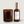 A dark amber glass candle jar and a matching amber bottle with a metallic gold cap and white label, both branded LUCERIA, on a light gray background.