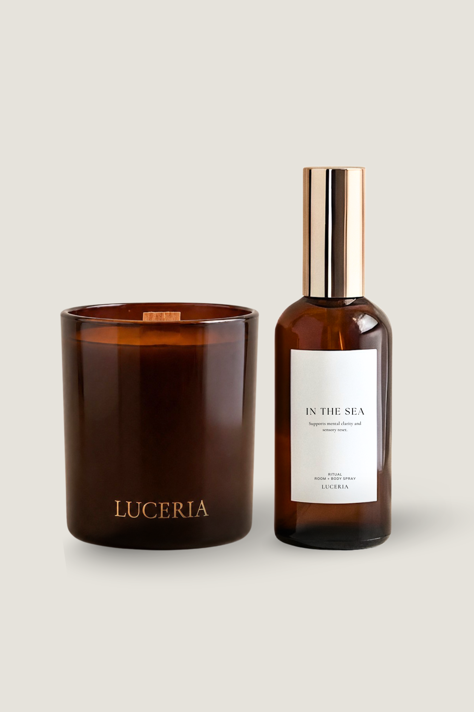 A luxury candle and room spray set by Luceria Candle Co., featuring an amber glass jar candle with gold lettering and a matching amber glass bottle with a metallic gold cap and white label, set against a solid light beige background.