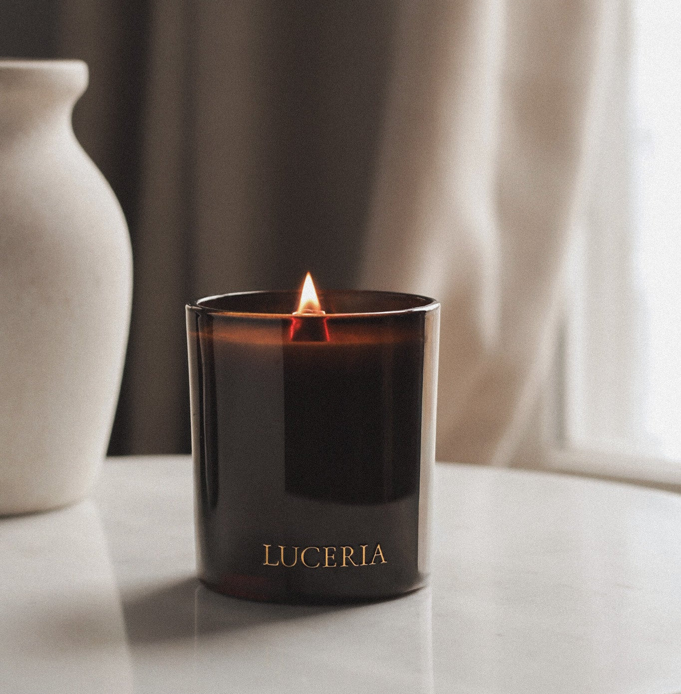 Luceria candle burning on a marble surface with a neutral background