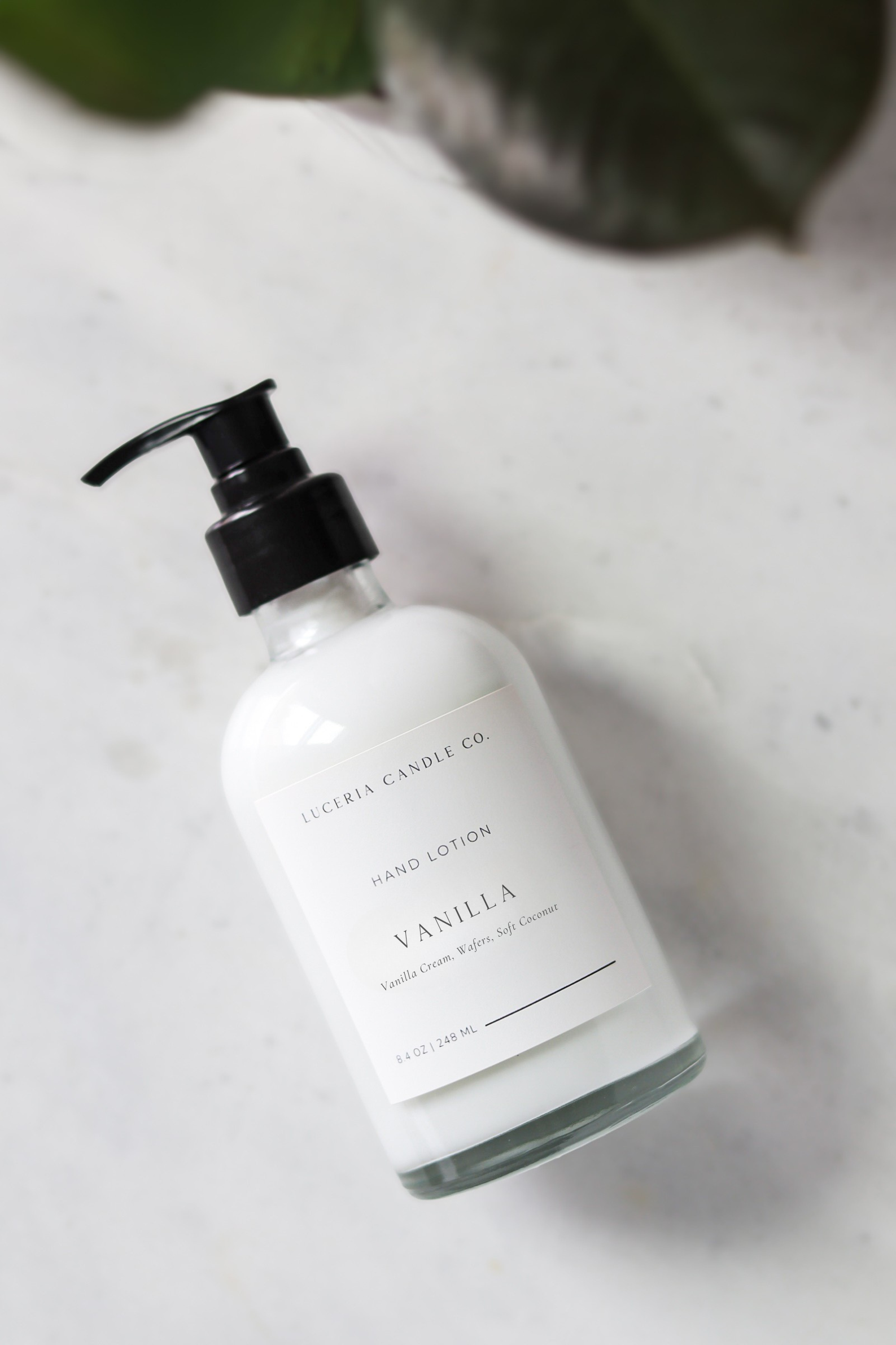 Vanilla lotion bottle with black pump on a light gray surface from Luceria candle co.
