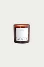 Soft eucalyptus scented candle with 'Woven' label on a beige background